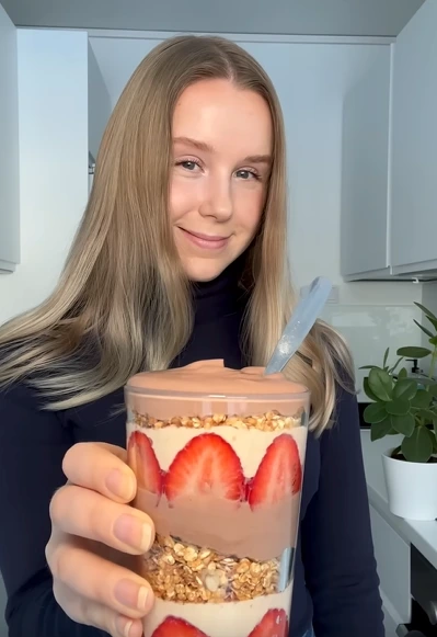 Greek yogurt protein parfait with granola, berries, honey, and walnuts in a glass jar