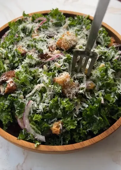 Tahini kale protein bowl with quinoa, tofu, edamame, kale, red onion, nuts, and green tahini sauce