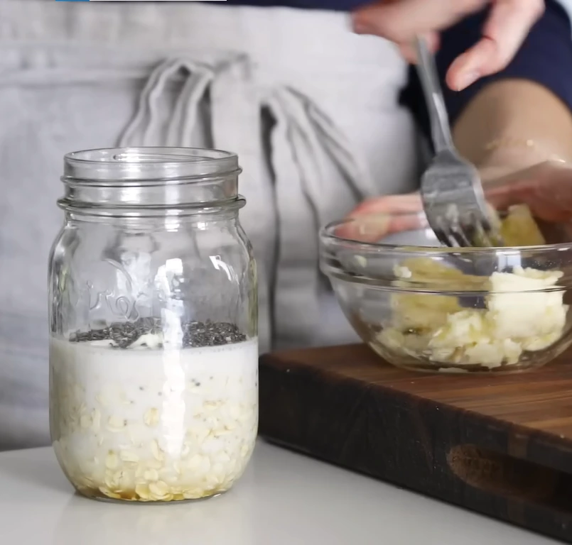 Overnight oats in jars with banana, peanut butter, berries, and chia seeds