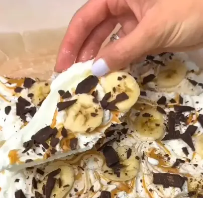 Chocolate banana yogurt bark broken into pieces with banana slices, walnuts, chocolate chips, and dark chocolate drizzle