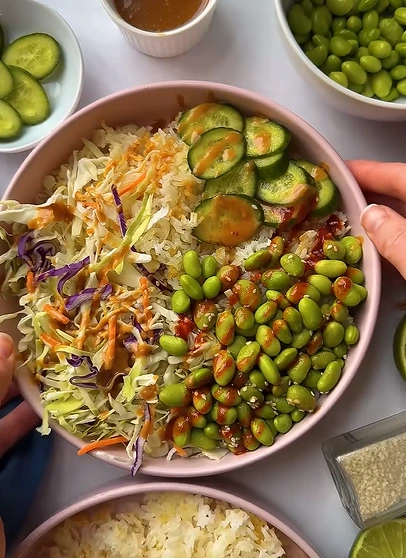 Edamame rice bowl with shredded carrots, almond butter sauce, chili crisp, and roasted peanuts