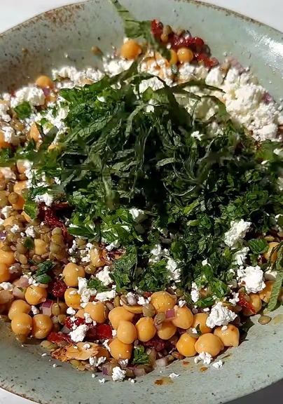 Loaded vegan lentil and chickpea salad with greens, red cabbage, carrots, avocado, and tahini dressing