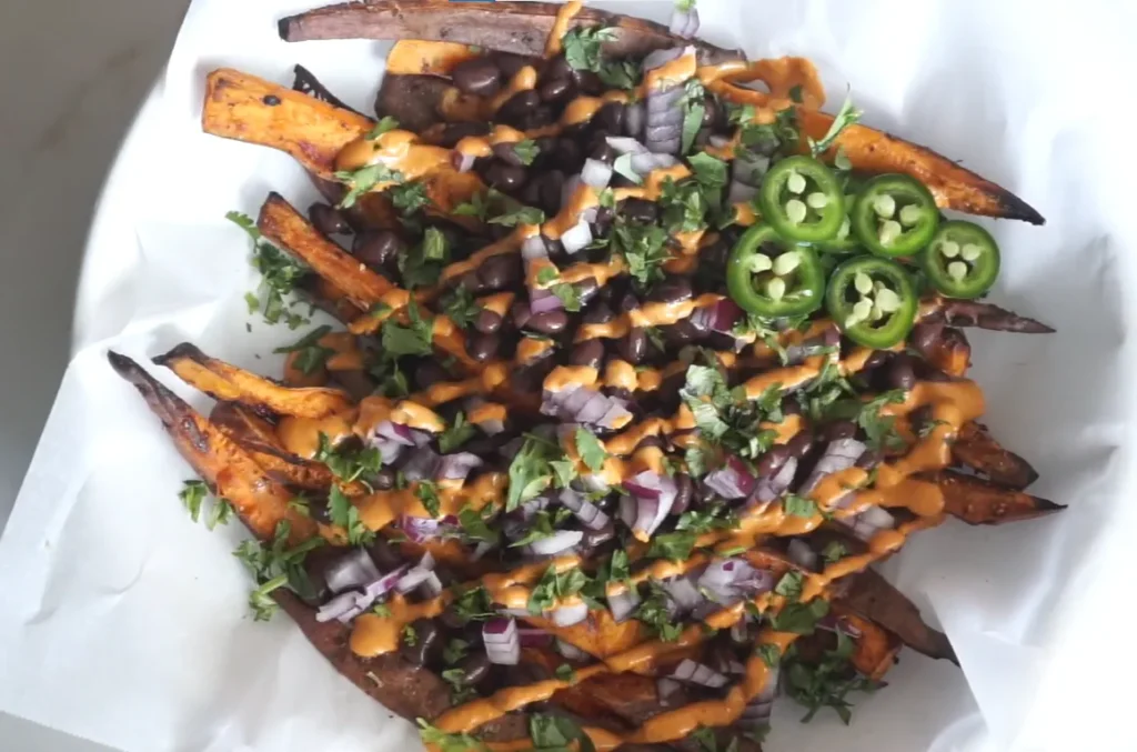 Loaded sweet potato fries with seasoned plant-based filling and vegan queso