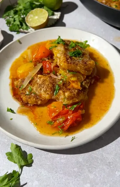 Mediterranean fish stew with white fish, tomatoes, potatoes, carrots, parsley, and crusty bread.