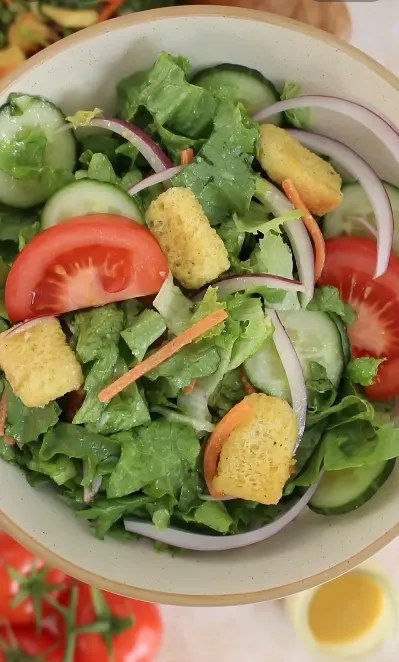 Simple house salad with Thousand Island dressing, tomatoes, cucumber, cheese, and croutons