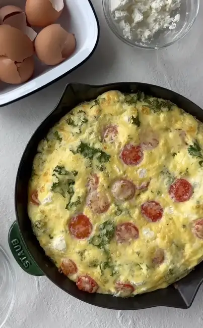 Spinach and ricotta frittata baked in a cast iron skillet and sliced into wedges.