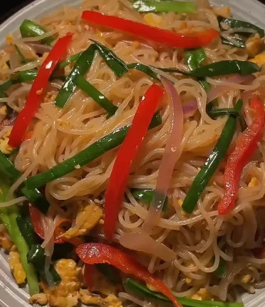 Rice noodle stir fry with vegetables, egg, and fresh herbs