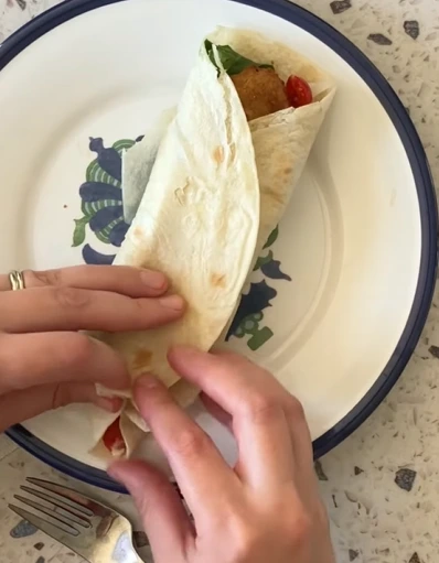 Turkey pinwheel roll-ups packed with hummus, carrot sticks, grapes, chips, and a small cookie