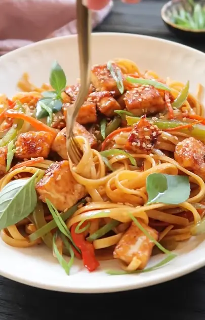 Vegan stir-fry noodles with pan-fried tofu, broccoli, carrots, and bell peppers
