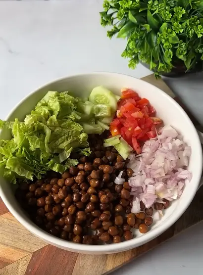 Black chickpea salad with cucumber, tomato, potato, onion, lemon, cilantro, and Indian spices in a clear lunch container