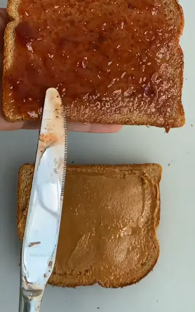 Classic peanut butter and jelly sandwich packed in a kids school lunchbox with fruit, pretzels, and a small cookie