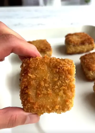 Crispy sesame panko tofu pieces baked until golden brown with a dipping sauce on the side
