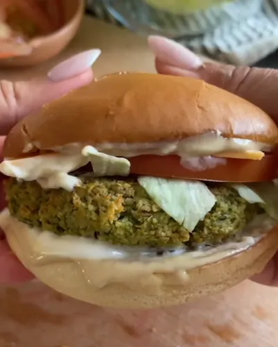 Loaded vegan burger with creamy chickpea sauce, avocado, pickles, lettuce, tomato, and crispy onion rings